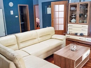 Ein Wohnzimmer mit einem beigefarbenen Sofa, einem Holztisch und einer Vitrine mit Glastüren.