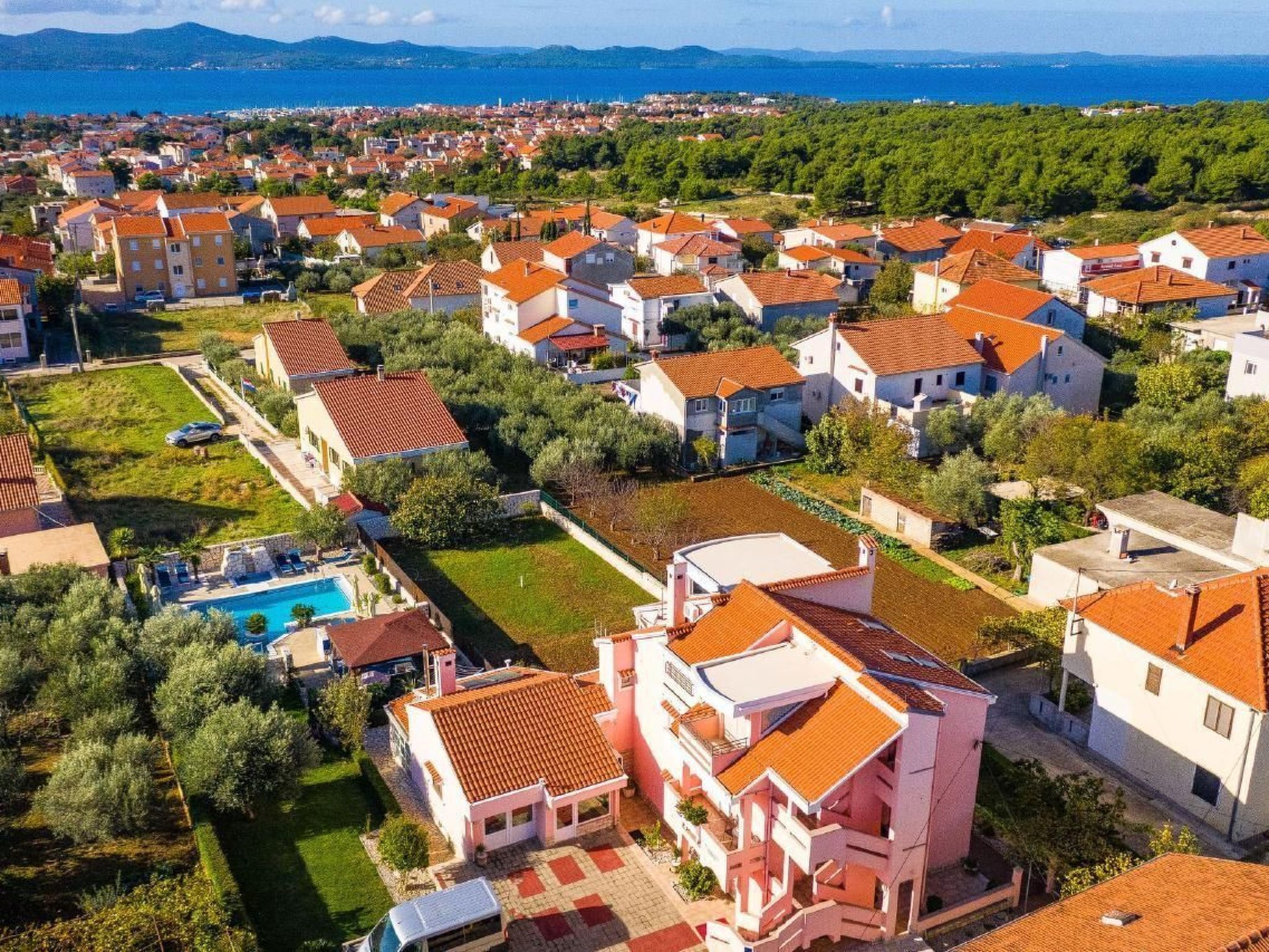 Un quartier résidentiel avec des maisons, une piscine et une vue sur la mer.