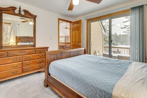 A bedroom with a large bed, a dresser, a mirror, and a sliding glass door leading to a balcony. - Snowmobile Trails & Ice Fishing in Wakefield (Sanbornville)