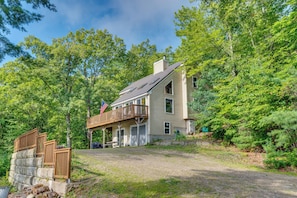 A two-story house with a deck, surrounded by trees. - Snowmobile Trails & Ice Fishing in Wakefield (Sanbornville)