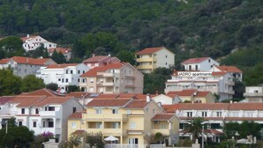 A coastal residential area with multi-story buildings, a stone wall, and a small green archway. - Insel Rab Jadro by Interhome (Rab/Rab)