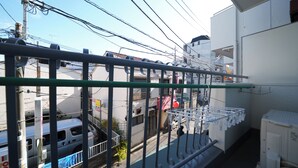 Uma varanda com grade de metal, um varal e uma caixa utilitária branca.