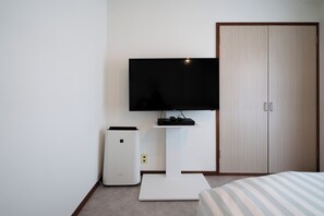Una camera da letto con un letto, una TV, un piccolo tavolino bianco e un armadio.