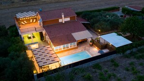 Una casa moderna con piscina, mobiliario exterior y zona de patio cubierta.