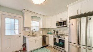 A modern kitchen with white cabinets, stainless steel appliances, a microwave, oven, and a refrigerator. - 6 Mi to Raymond James Stadium: Tampa Retreat! (Tampa)