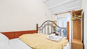 A bedroom with a bed, a wooden wardrobe, and a balcony with a railing. - Panoramare by Interhome (Plomin)
