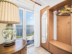 A room with a wooden wardrobe, a mirror, and a table with a lamp. There is a balcony with a view of the landscape. - Panoramare by Interhome (Plomin)