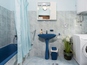 Un baño con un lavabo azul, una bañera, un inodoro y una lavadora.