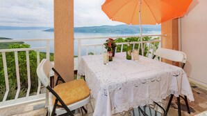 A balcony with a table set for two, overlooking a body of water and hills. - Panoramare by Interhome (Plomin)