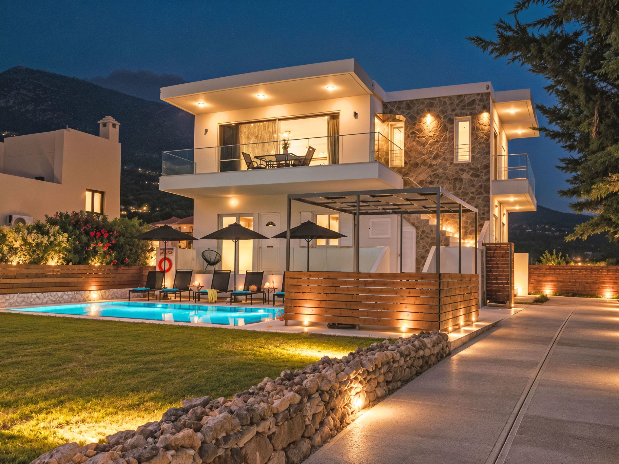 A modern two-story house with a swimming pool, outdoor seating, and a stone facade.