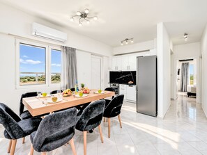 A modern kitchen with a dining area, large windows, and a view of the outdoors. - Luminosa Luxus-Villa by Interhome (Georgioupoli)