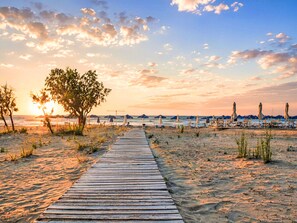 A wooden boardwalk leading to beach umbrellas and lounge chairs. - Luminosa Luxus-Villa by Interhome (Georgioupoli)