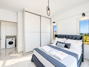 A modern bedroom with a large bed, a washing machine, and a view of the sea. - Luminosa Luxus-Villa by Interhome (Georgioupoli)