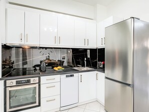 A modern kitchen with white cabinets, stainless steel appliances, and a black countertop. - Luminosa Luxus-Villa by Interhome (Georgioupoli)