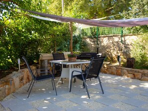Eine Terrasse im Freien mit Tisch und Stühlen, umgeben von Steinmauern und Pflanzen.