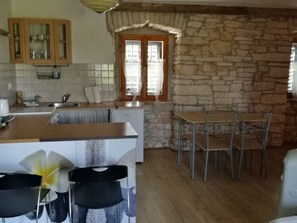Eine Küche mit Steinwand, Holzschränken und einem Essbereich mit Stühlen und Tisch.