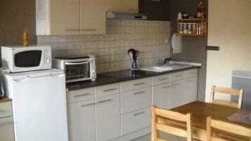 Een koelkast, een microgolfoven, een oven, kookgerei, borden en bestek