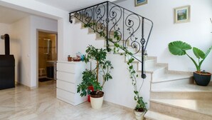 A modern interior with a staircase, a white wall, and a potted plant.
