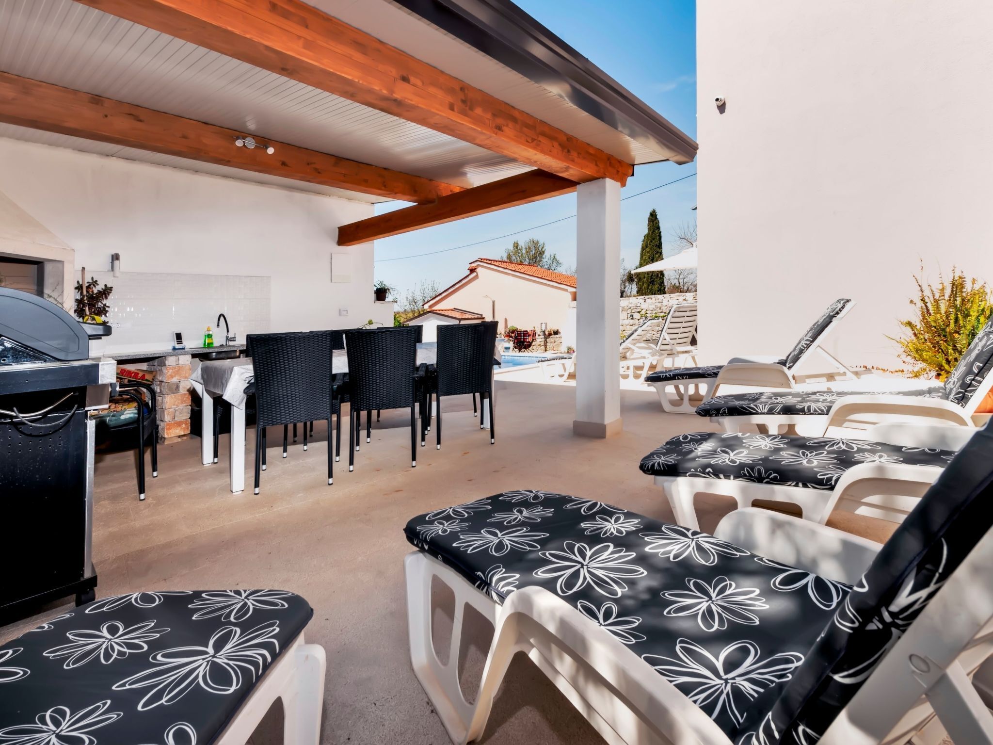 An outdoor patio area with a grill, dining table, and chairs.