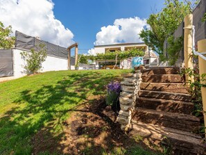 Ein Wohnhaus mit einer Steintreppe, einem Rasen und blauem Himmel.