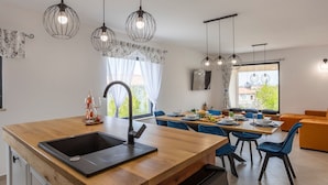 Eine moderne Küche mit einer Holz Arbeitsplatte, einem schwarzen Spülbecken und Pendelleuchten.