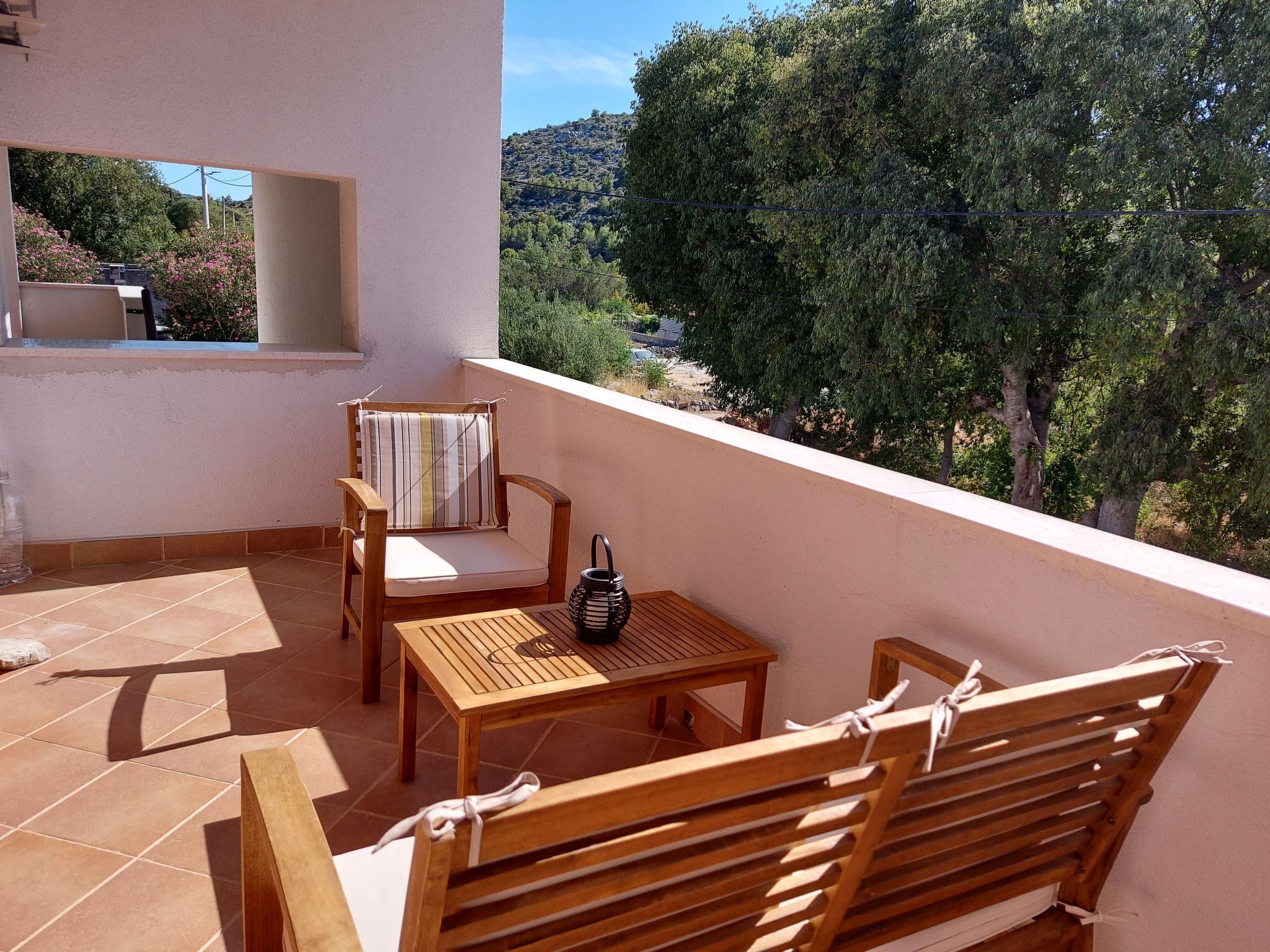 A balcony with a wooden table, two chairs, and a small table.