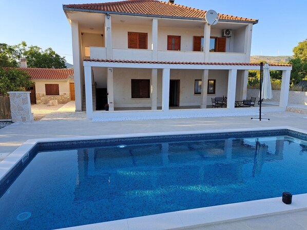 Ein zweistöckiges Haus mit Schwimmbad davor.