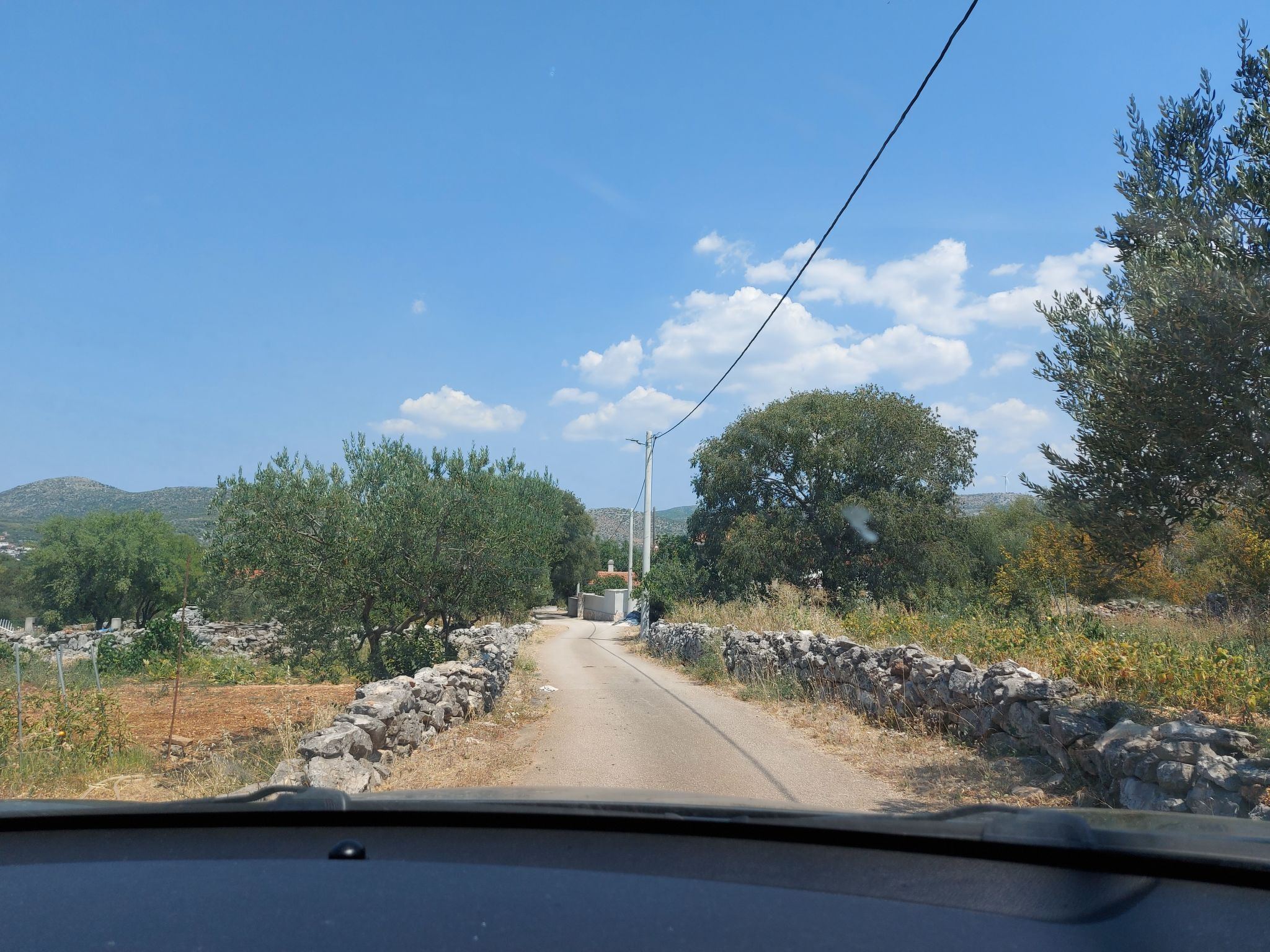 A rural road with stone walls and trees on both sides.