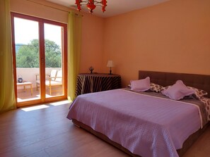 Ein Schlafzimmer mit einem Bett, einem Nachttisch, einer Lampe, einem Sessel und einem Tisch neben einer Schiebetür.