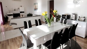 Een moderne keuken met witte kastjes, een eettafel met zwarte stoelen en een vaas met gele bloemen.