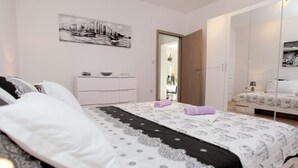 Een moderne slaapkamer met een groot bed, een dressoir en een kledingkast.