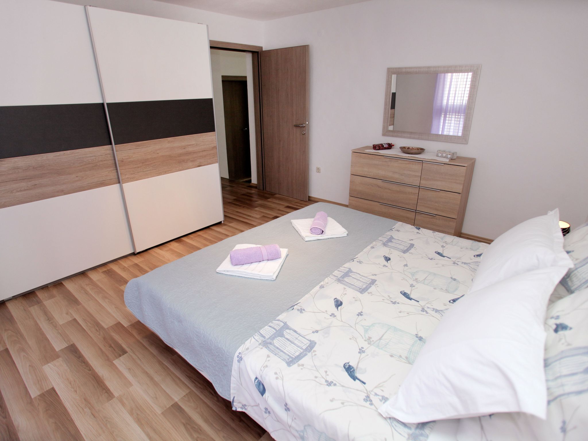 A bedroom with a bed, a dresser, a mirror, and a wardrobe.