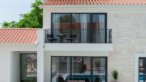 Ein zweistöckiges Haus mit Balkon, Sitzgelegenheit im Freien und einem Schwimmbad.
