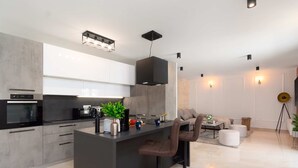 Eine moderne Küche mit Kochinsel, Barhocker und Essbereich mit Sofa und Couchtisch.