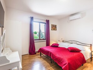 A bedroom with a bed, a window with curtains, a radiator, and an air conditioning unit. - Wohnung "Wohnung Sterna mit Pool" by Interhome (Svetvinčenat)