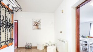 A spacious living area with a tiled floor, a dining table with chairs, a sofa, and a radiator. - Wohnung "Wohnung Sterna mit Pool" by Interhome (Svetvinčenat)