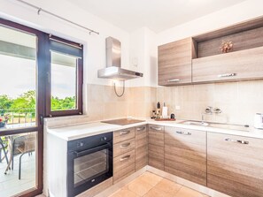 A modern kitchen with a built-in oven, a window with a view, and wooden cabinetry. - Wohnung "Wohnung Sterna mit Pool" by Interhome (Svetvinčenat)