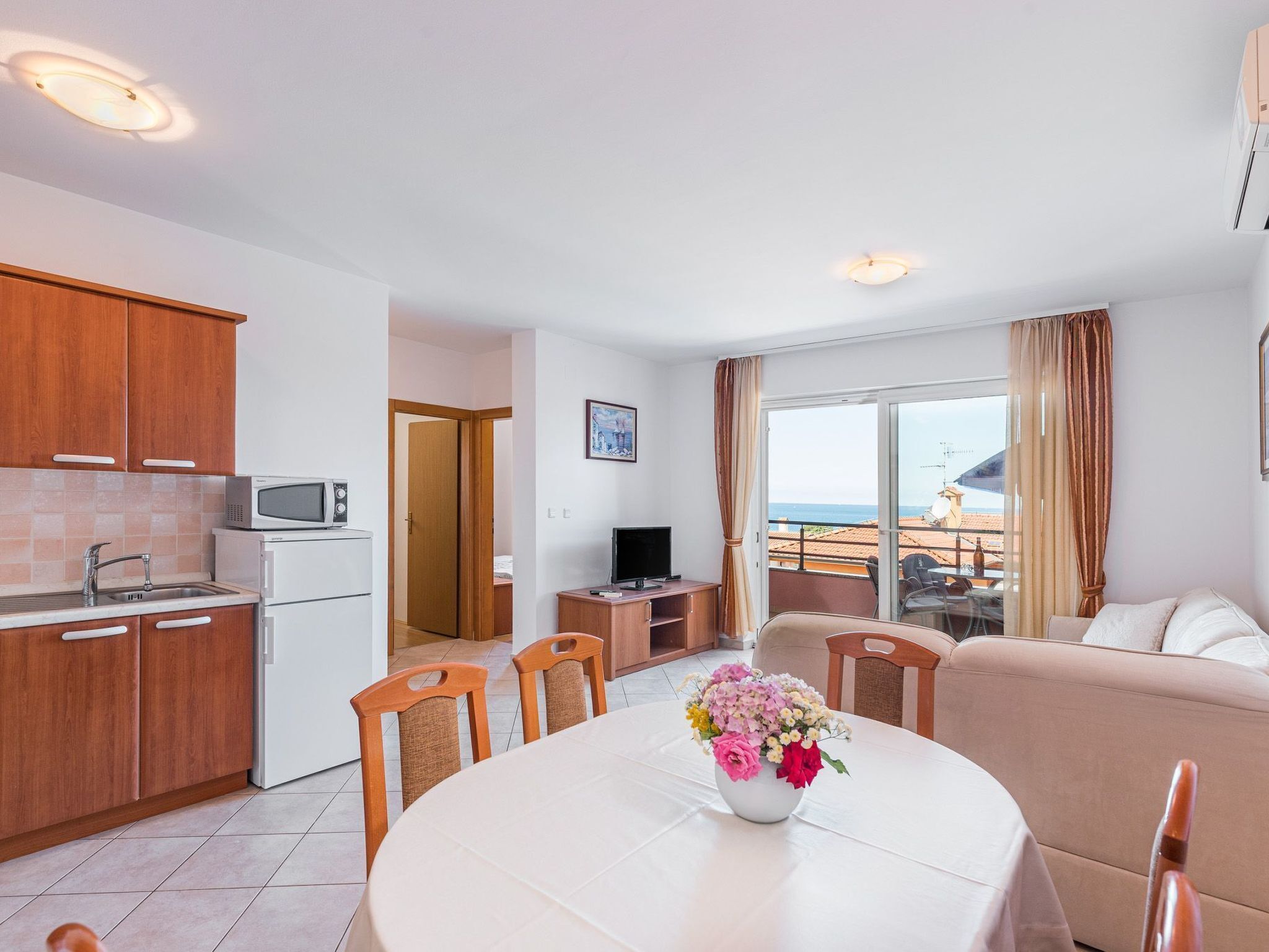 Een modern appartement met keuken, eethoek en woonkamer. Het heeft een balkon met uitzicht op zee.