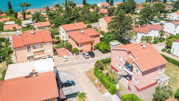 Vista aérea de uma área residencial costeira com casas, um porto de iates e barcos.