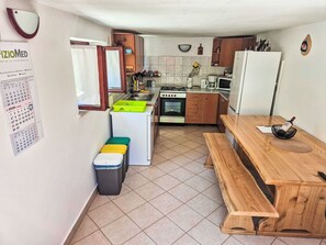 A compact kitchen with a stove, sink, and wooden table. - Gemütliches kleines schönes Haus für max. 4 Personen by Interhome (Kraljevica)