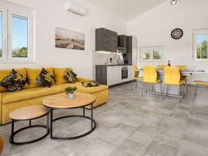 A modern kitchen with grey cabinets, a microwave, and a stove. There is a dining area with yellow chairs and a table. A yellow sofa with patterned cushions is in the living area. - Villa mit privatem Pool in einer ruhigen Gegend gelegen by Interhome (Pula/Krnica)