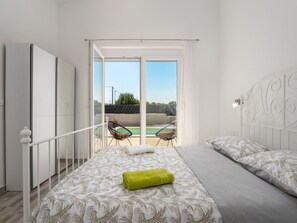 A bedroom with a bed, a balcony with chairs, and a view of a swimming pool. - Villa mit privatem Pool in einer ruhigen Gegend gelegen by Interhome (Pula/Krnica)