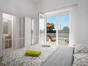 A bedroom with a bed, a bathroom, and a balcony with a pool. - Villa mit privatem Pool in einer ruhigen Gegend gelegen by Interhome (Pula/Krnica)