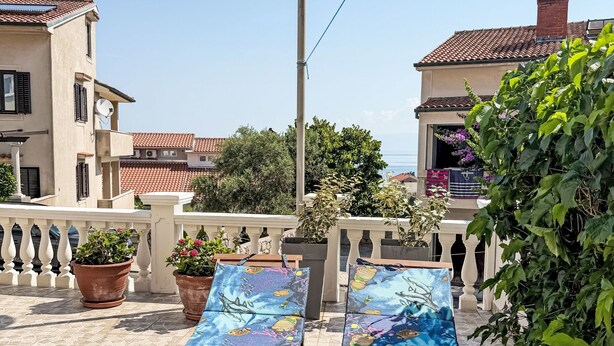 A terrace with two lounge chairs, potted plants, and a view of the sea and buildings. - Studioapartment Meri 4 by Interhome (Losinj / Mali Losinj)