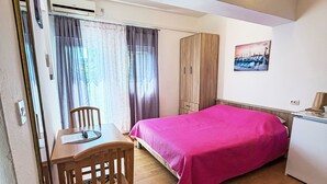 A bedroom with a bed, a desk, a chair, a wardrobe, and a painting on the wall. - Studioapartment Meri 4 by Interhome (Losinj / Mali Losinj)
