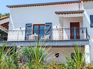 A white building with a balcony, a door, and a window. - Lucinkas Ferienhaus mit 2 Schlafzimmern by Interhome (La Tour sur Orb)