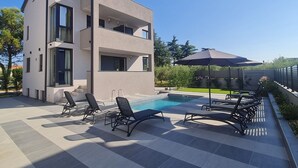 Ein modernes, zweistöckiges Gebäude mit Pool, Außenbereich und einer Pergola.