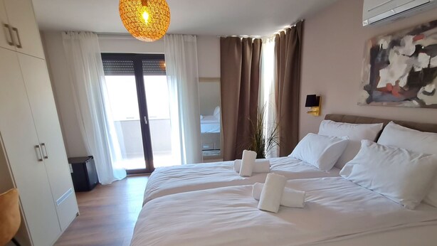 Ein Hotelzimmer mit einem großen Bett, einer Deckenleuchte, Blick ins Freie und einem Gemälde an der Wand.