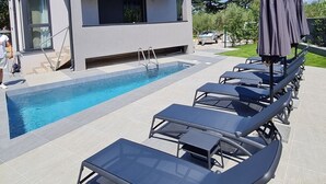 Ein modernes Gebäude mit Pool und Liegestühlen.