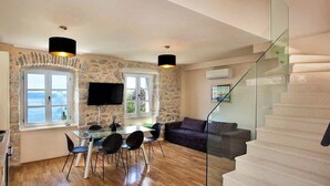 Un salón amplio con una mesa de comedor, sillas, un sofá, un televisor y una escalera.
